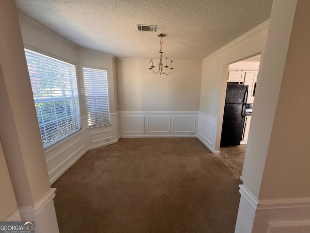 unfurnished dining area featuring crown molding, a textured ceiling, a chandelier, and dark carpet