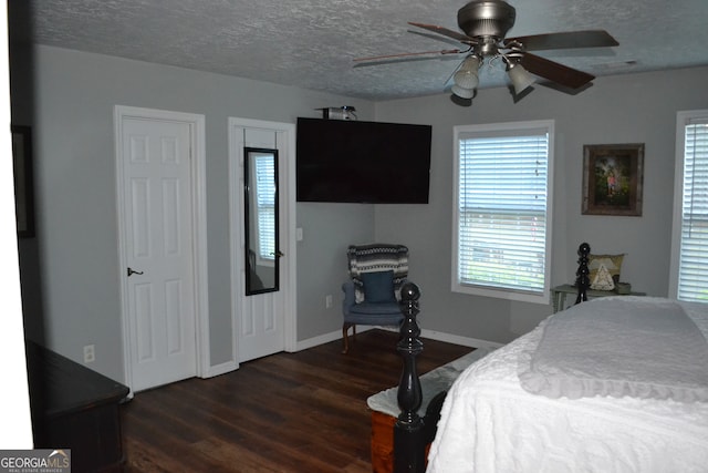 bedroom featuring ceiling fan, two closets, dark hardwood / wood-style floors, and a textured ceiling