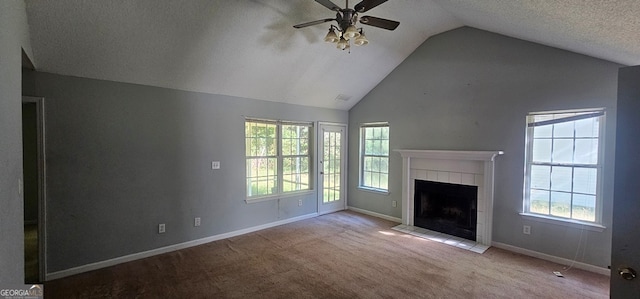 unfurnished living room featuring ceiling fan, a fireplace, vaulted ceiling, and a wealth of natural light