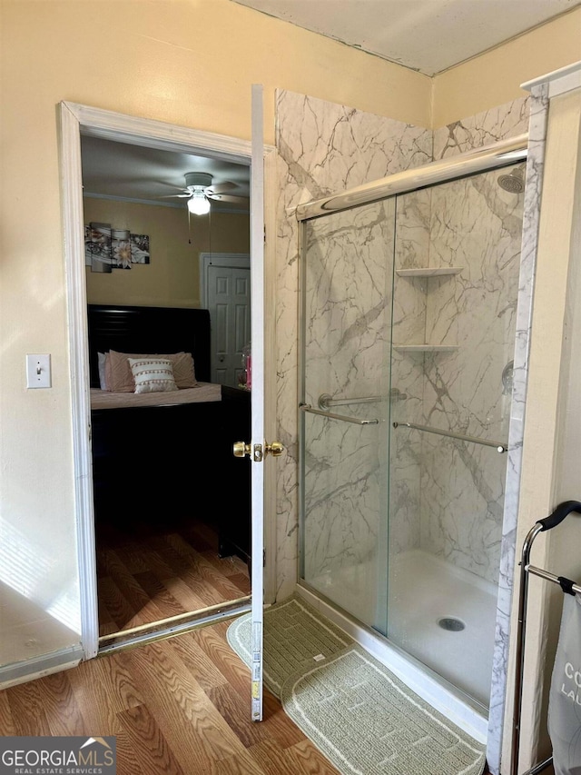 bathroom featuring ceiling fan, hardwood / wood-style floors, and a shower with door