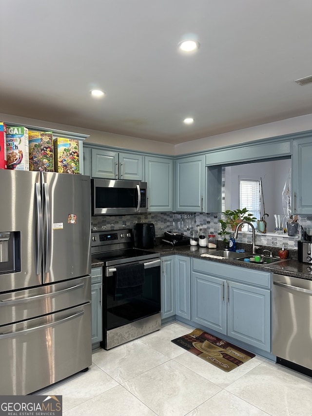 kitchen with blue cabinetry, decorative backsplash, stainless steel appliances, and sink