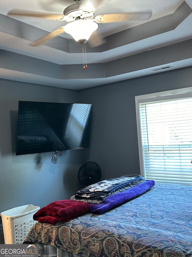 bedroom featuring ceiling fan and a raised ceiling