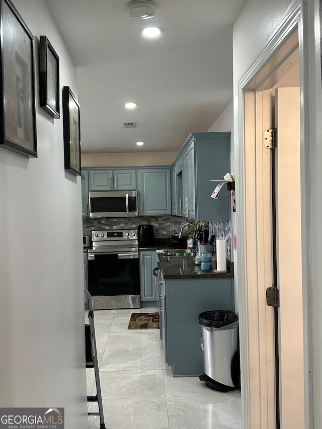 kitchen featuring tasteful backsplash, appliances with stainless steel finishes, sink, dark stone countertops, and light tile patterned floors