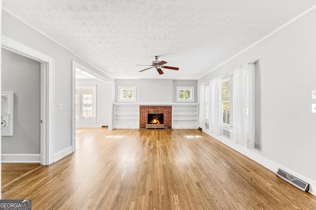 unfurnished living room featuring ceiling fan, plenty of natural light, wood-type flooring, and a textured ceiling