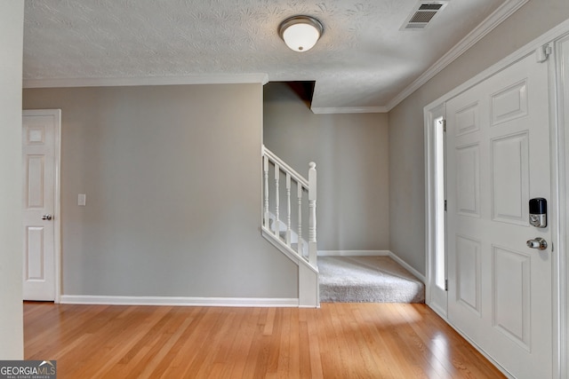 entrance foyer featuring hardwood / wood-style flooring, a textured ceiling, and ornamental molding