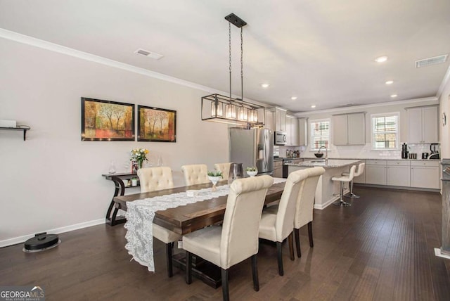 dining space featuring sink, crown molding, and dark hardwood / wood-style flooring