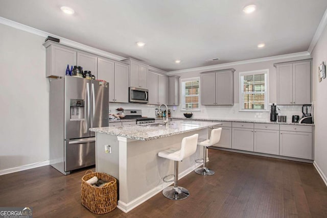 kitchen with light stone countertops, dark wood-type flooring, a center island, and stainless steel appliances