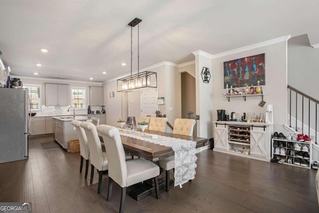 dining area with ornamental molding, sink, and dark hardwood / wood-style flooring