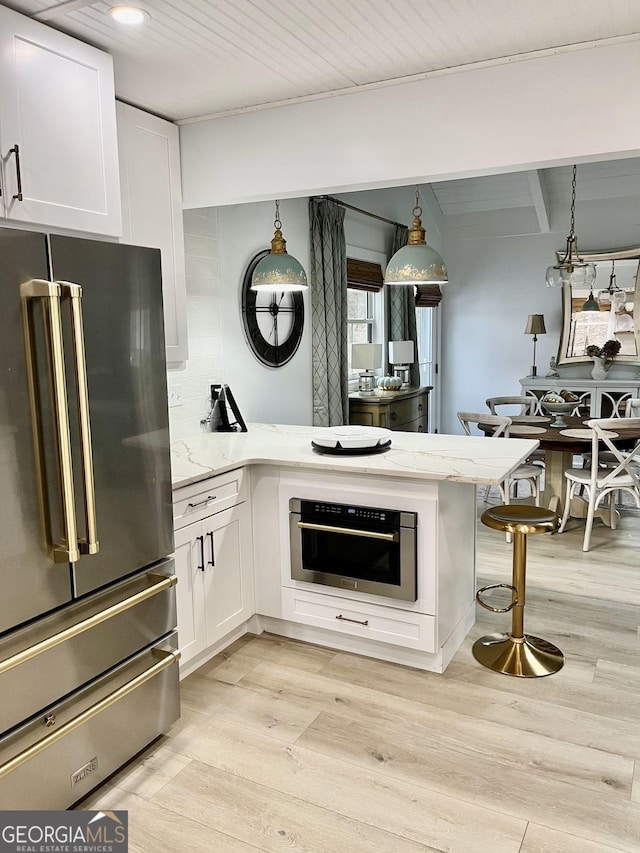 kitchen with white cabinetry, a breakfast bar, appliances with stainless steel finishes, and kitchen peninsula