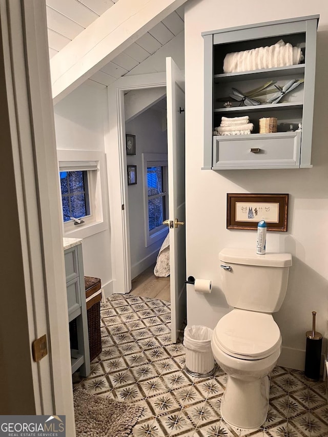 bathroom with lofted ceiling, toilet, and vanity