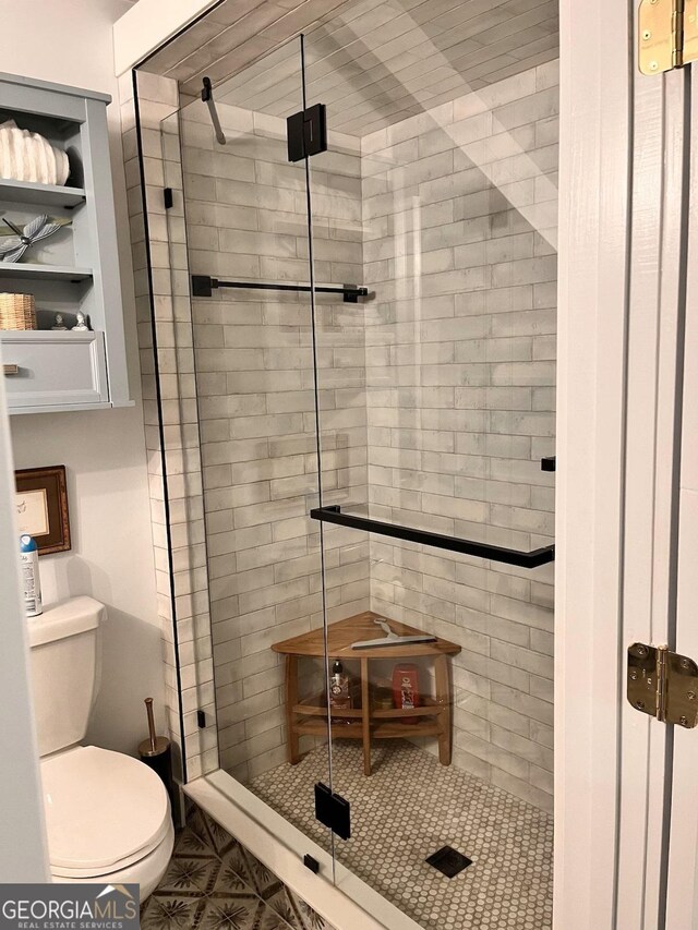 bathroom featuring toilet and a shower with shower door