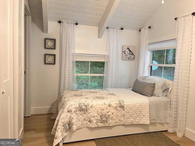 bedroom with multiple windows, light wood-type flooring, and lofted ceiling with beams