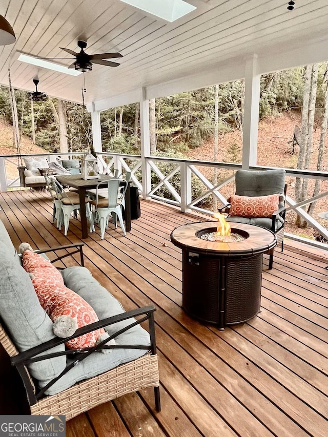 sunroom / solarium featuring ceiling fan, a skylight, and wooden ceiling