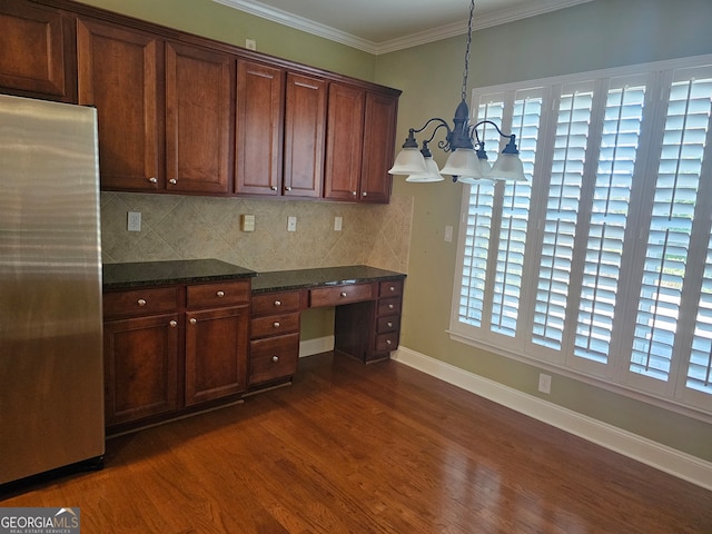 kitchen with stainless steel refrigerator, dark wood-type flooring, dark stone countertops, decorative light fixtures, and built in desk