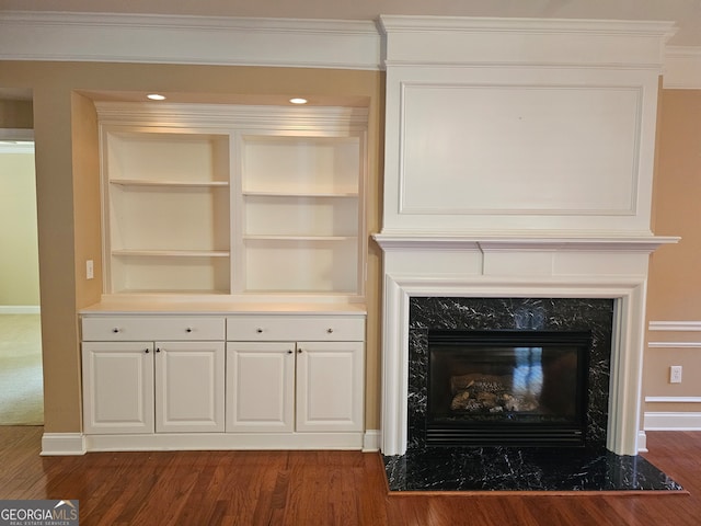 interior details with built in shelves, hardwood / wood-style flooring, crown molding, and a high end fireplace