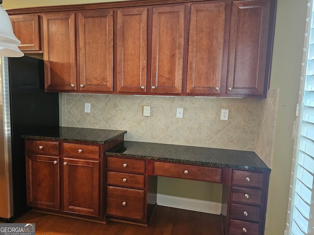 kitchen with fridge, built in desk, dark hardwood / wood-style floors, and tasteful backsplash