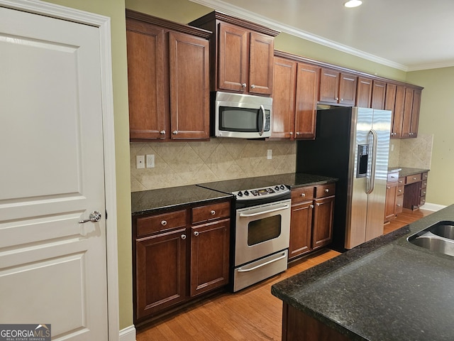 5911 Chimney Rock Dr, Hoschton, GA 30548 - kitchen featuring crown molding, tasteful backsplash, light wood-type flooring, dark stone countertops, and stainless steel appliances