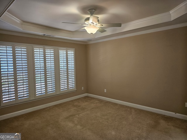 carpeted spare room with ceiling fan, a raised ceiling, and crown molding