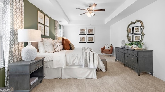 bedroom featuring light colored carpet, ceiling fan, and a raised ceiling