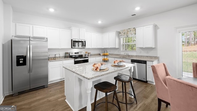 kitchen with stainless steel appliances, white cabinets, dark hardwood / wood-style flooring, and a center island