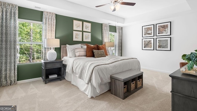 bedroom with multiple windows, ceiling fan, and light colored carpet