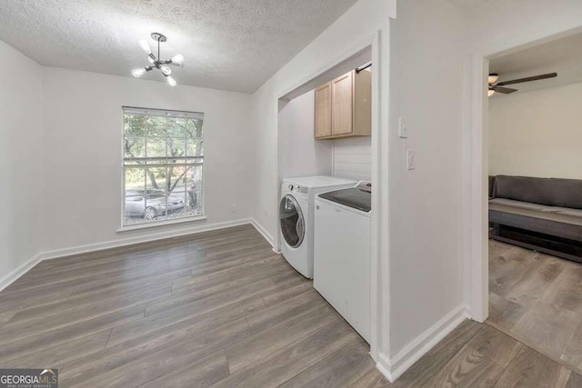 83 Sunset Ln, Newnan, GA 30263 - clothes washing area with a textured ceiling, wood finished floors, washing machine and clothes dryer, baseboards, and cabinet space