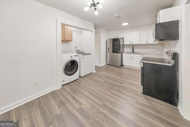 washroom featuring washing machine and clothes dryer, sink, light wood-type flooring, and a textured ceiling