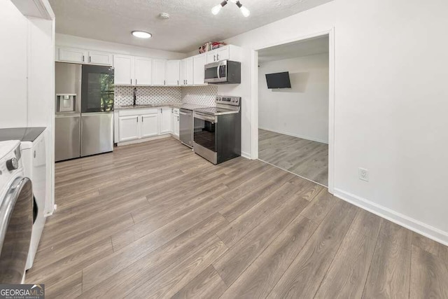 83 Sunset Ln, Newnan, GA 30263 - kitchen with white cabinets, appliances with stainless steel finishes, a sink, baseboards, and backsplash