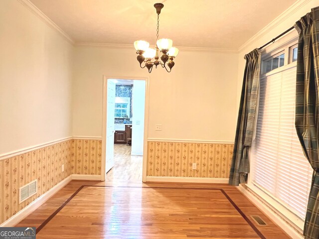 unfurnished room featuring ornamental molding, wood-type flooring, and a chandelier