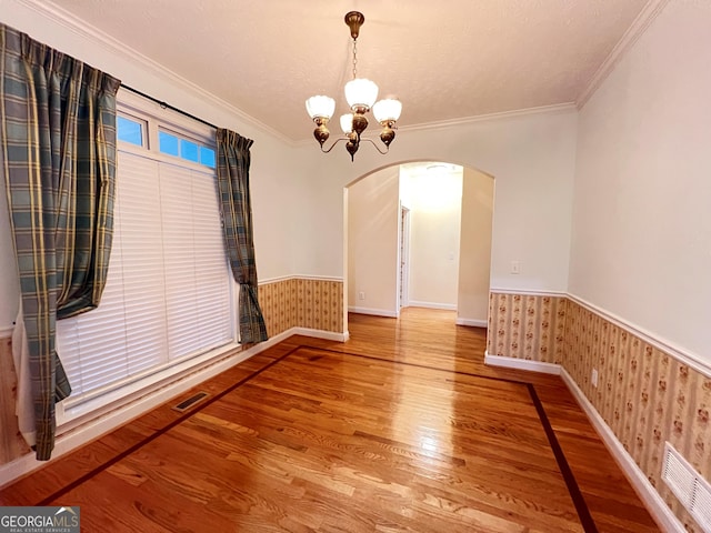 unfurnished dining area featuring hardwood / wood-style flooring, ornamental molding, a chandelier, and a textured ceiling