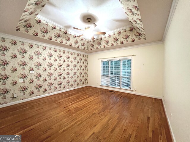 spare room with a raised ceiling, ornamental molding, hardwood / wood-style floors, and ceiling fan