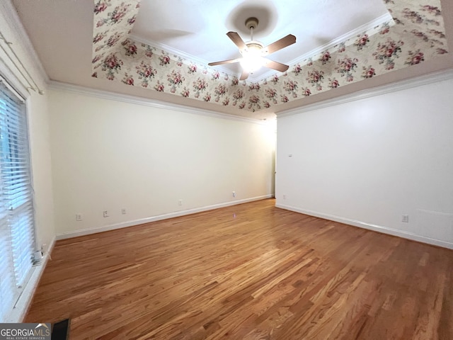 unfurnished room with hardwood / wood-style flooring, ceiling fan, ornamental molding, and a raised ceiling