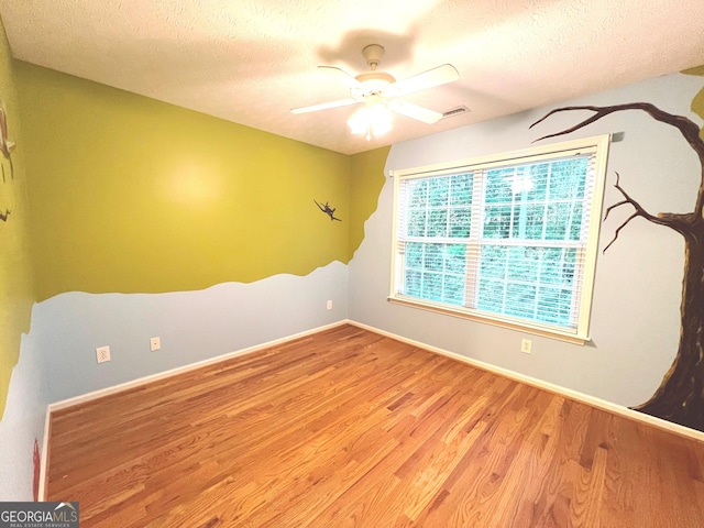 unfurnished room featuring ceiling fan, light hardwood / wood-style flooring, and a textured ceiling