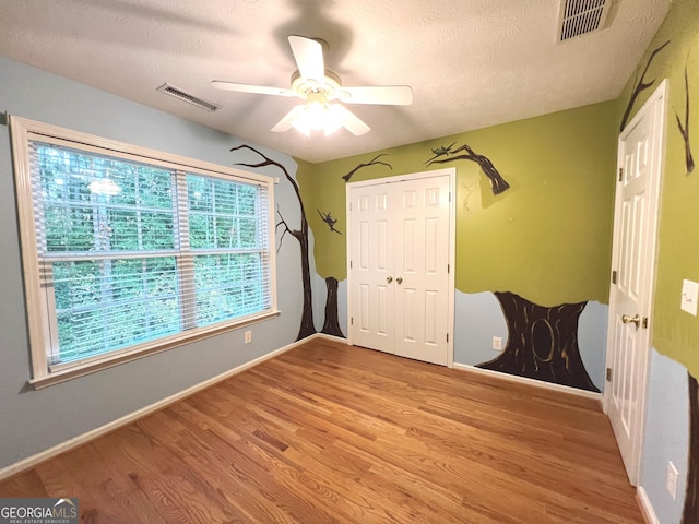 interior space featuring ceiling fan, light hardwood / wood-style flooring, a closet, and a textured ceiling