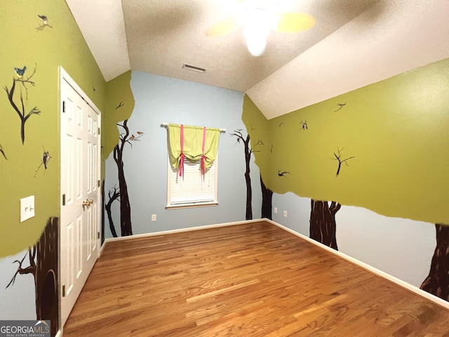 spare room featuring vaulted ceiling, light hardwood / wood-style flooring, and a textured ceiling