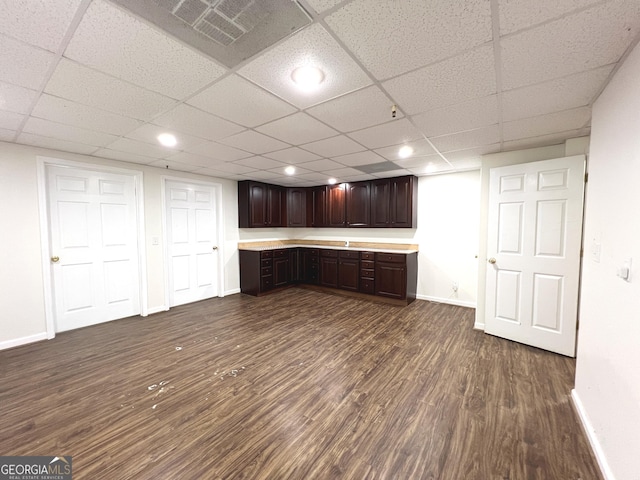 kitchen with dark brown cabinetry, dark hardwood / wood-style flooring, and a drop ceiling