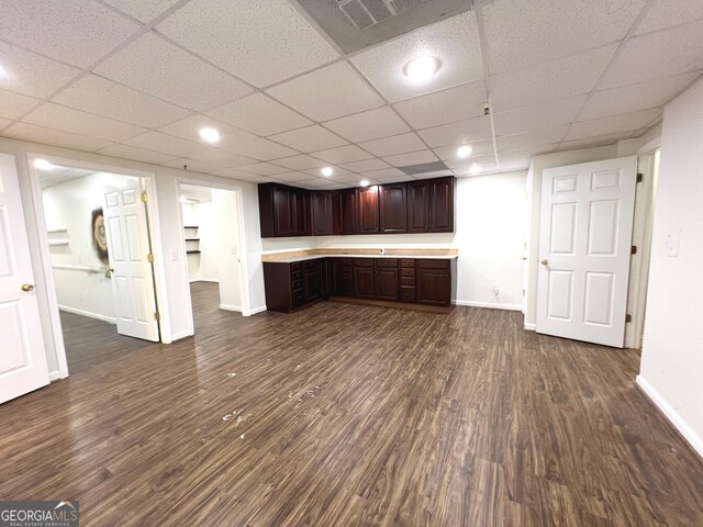 kitchen featuring dark hardwood / wood-style flooring, built in desk, a drop ceiling, and dark brown cabinetry