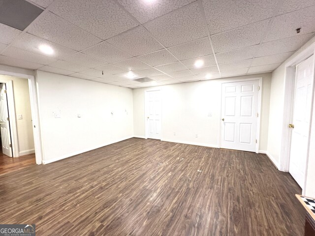 basement featuring a paneled ceiling and dark hardwood / wood-style floors