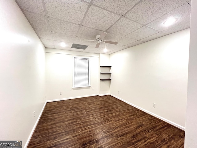 basement featuring dark hardwood / wood-style flooring, a paneled ceiling, and ceiling fan