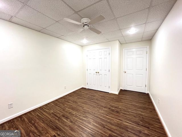 unfurnished bedroom with dark hardwood / wood-style floors, a paneled ceiling, ceiling fan, and a closet