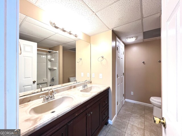 bathroom featuring a paneled ceiling, tile patterned floors, and toilet