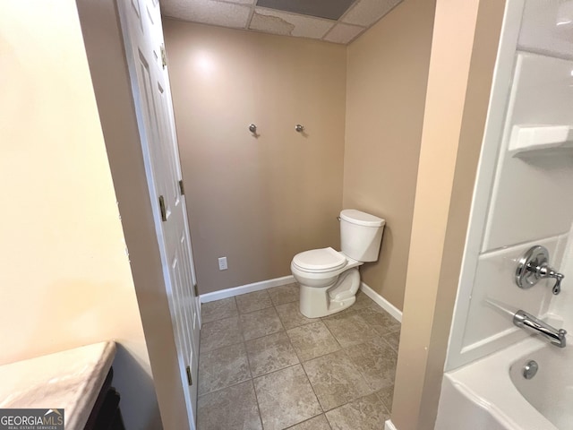 bathroom featuring a paneled ceiling, tile patterned floors, and toilet