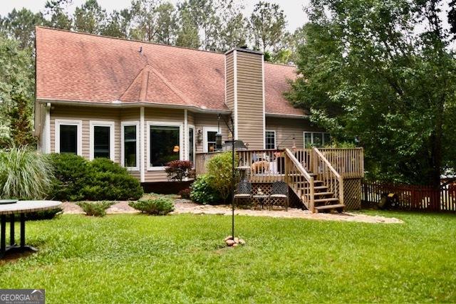 back of property with a wooden deck and a lawn