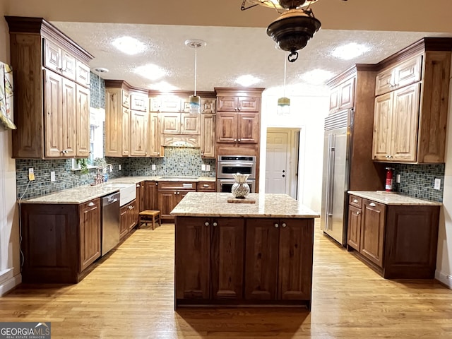 kitchen featuring hanging light fixtures, light wood-type flooring, stainless steel appliances, and a kitchen island