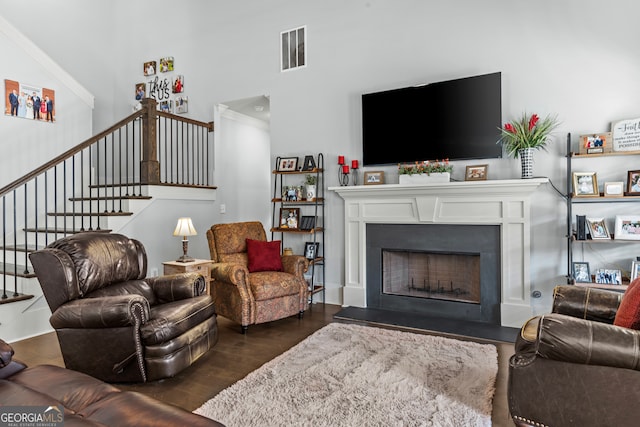 living room with dark wood-type flooring, ornamental molding, and a towering ceiling