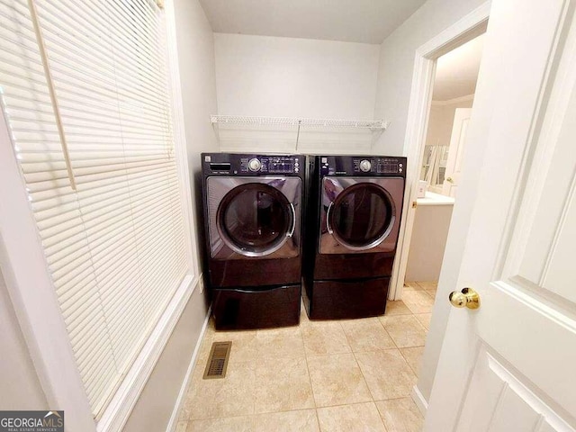 laundry room featuring washing machine and dryer and light tile patterned flooring