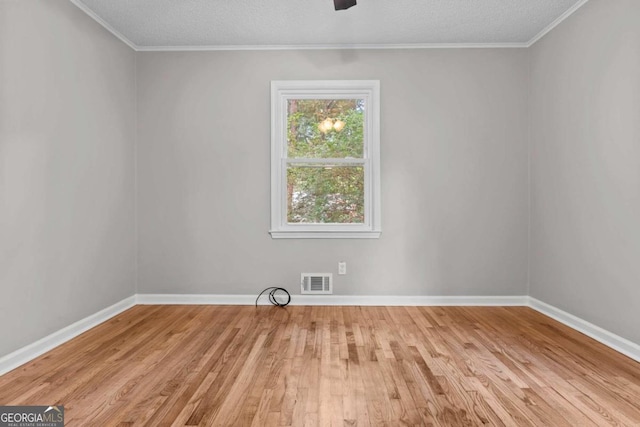 spare room featuring a textured ceiling, light wood-type flooring, and ornamental molding