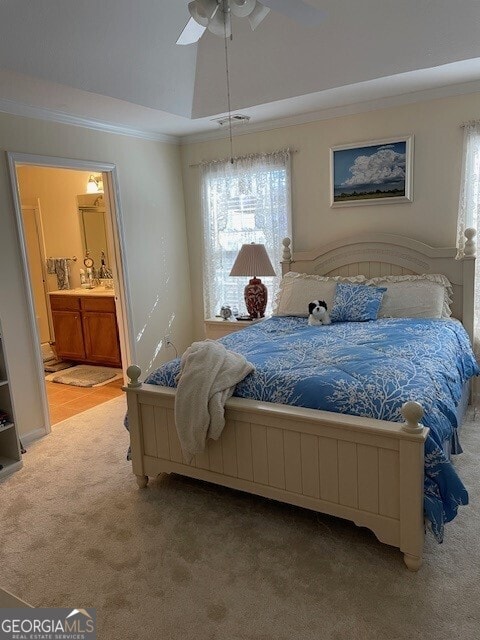 carpeted bedroom with multiple windows, connected bathroom, ornamental molding, and a raised ceiling