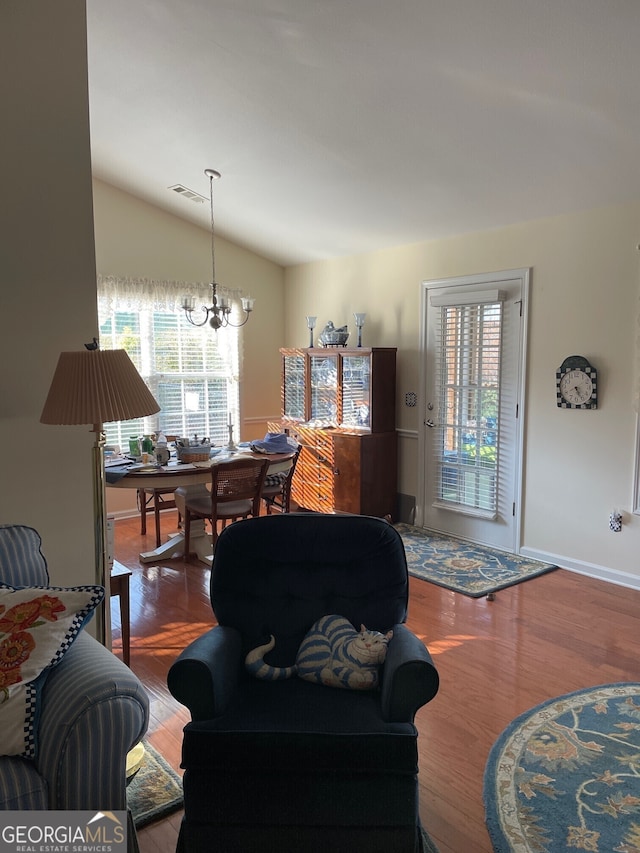 living room featuring lofted ceiling, hardwood / wood-style floors, and a notable chandelier