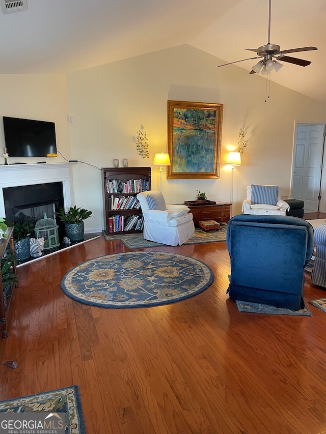 living room with ceiling fan, wood-type flooring, and vaulted ceiling